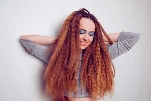 Redheaded woman wearing a grey top with crimped hair
